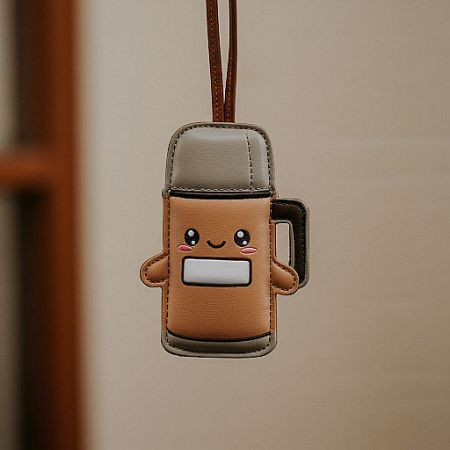 A cute coffee cup-shaped leather keychain with a smiling cartoon face, perfect for promotional gifts.