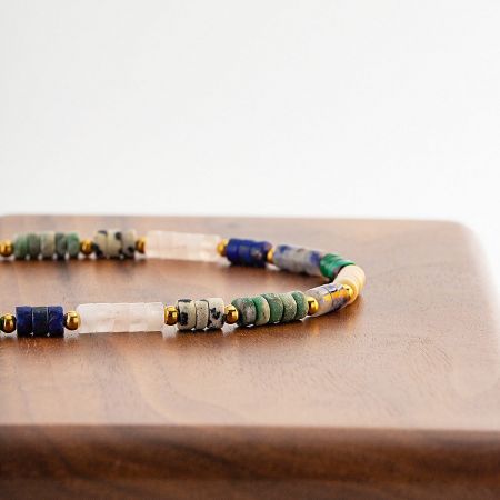 The unique, colorful beaded bracelet displayed on a rustic wooden stand.