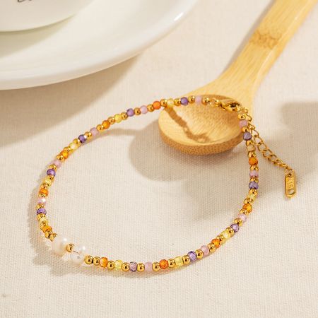 A flat lay of one of the colorful beaded anklets with gold components, showcasing its intricate design.
