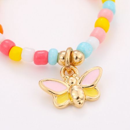 Detailed view of a beaded ring with a delicate gold butterfly charm.