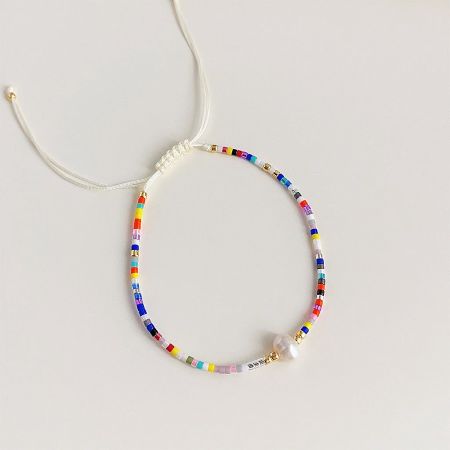 Close-up of a multi-colored bohemian beaded bracelet with a central pearl.