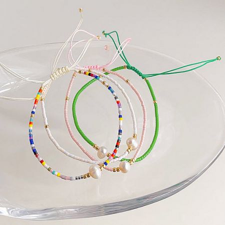 Costume Bracelets Collection - A diverse collection of colorful beaded and pearl costume bracelets from JR Fashion Accessories, elegantly displayed on a clear glass dish.