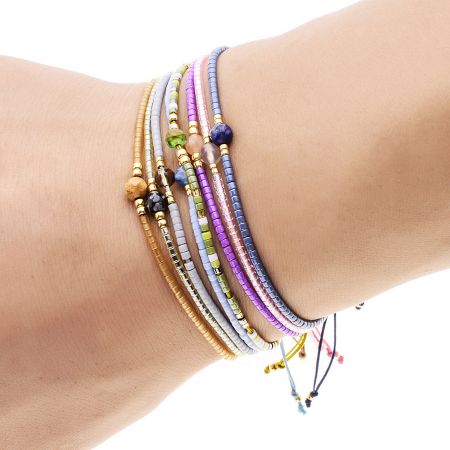 Multi-Color Bohemian Handwoven Bracelets with Natural Stones (Set of 5) - A stack of multi-color bohemian handwoven bracelets featuring small rice beads and natural stones, worn on a wrist.