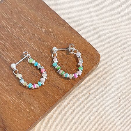 A pair of colorful beaded hoop earrings with a mix of red, yellow, and blue beads.