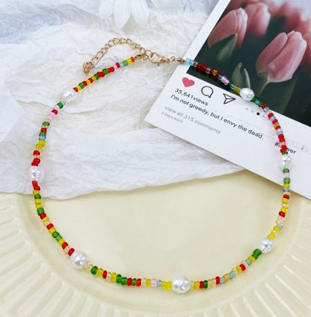 Detailed view of the gold lobster clasp on the colorful beaded pearl necklace.