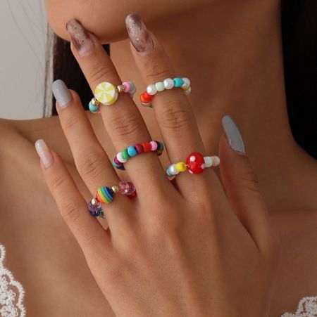 Close-up of a hand wearing multiple colorful beaded rings, showcasing a popular style from the Spring/Summer collection.
