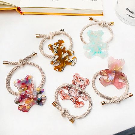 Close-up of five elastic hair ties, each with a different colored acetate bear charm.