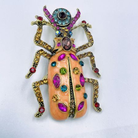 Elegant peach-colored beetle brooch from the collection, featuring multi-colored gemstone accents.