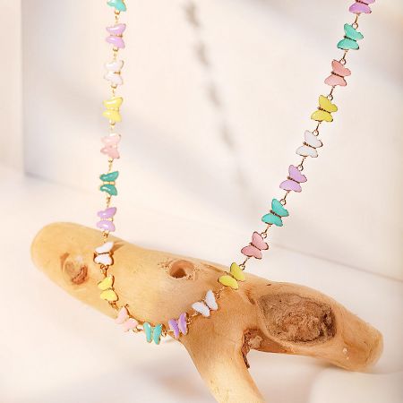 Butterfly charm necklace elegantly draped over natural driftwood.
