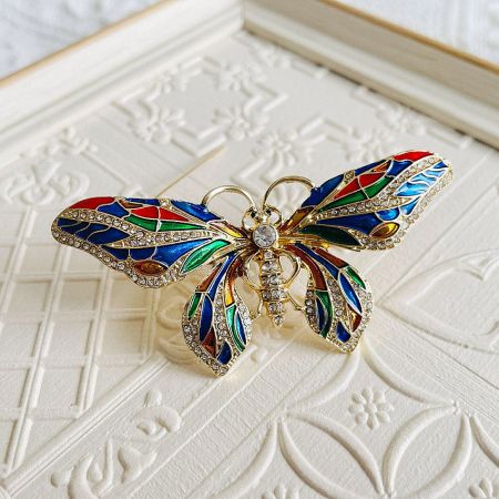The butterfly brooch with a gold base and vibrant stones on a white background.