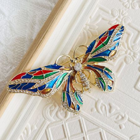 Angled view of the colorful butterfly brooch, emphasizing its sparkling stones and gold finish.