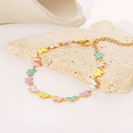 Detailed shot of the gold chain bracelet featuring multiple colorful butterfly charms.