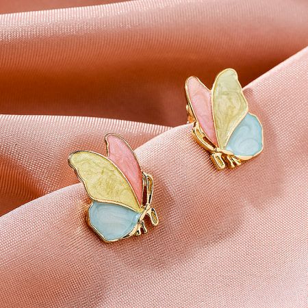 The colorful butterfly earrings displayed on a soft pink fabric background to highlight their design.