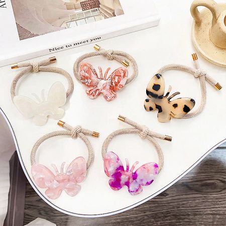 A set of five butterfly hair ties in different colors including pink, blue, and tortoiseshell.