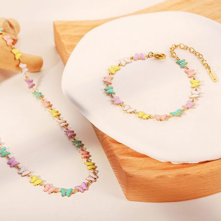 A complete jewelry set showcasing the matching colorful butterfly charm bracelet and necklace.