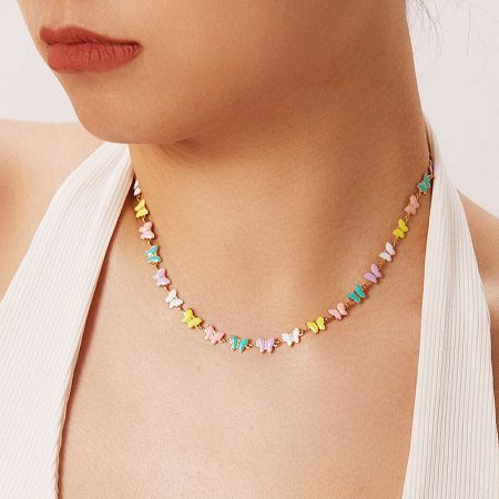Model showcasing the colorful butterfly necklace with a gentle smile.