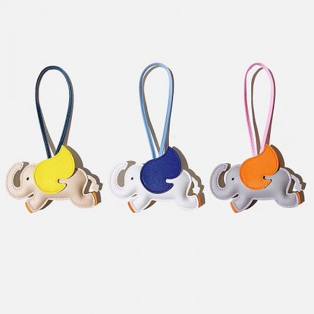 A collection of three colorful PU leather elephant bag charms in white, grey, and ivory, showcasing the available color options.