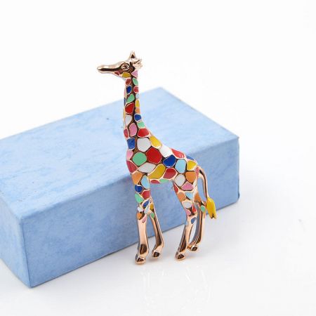 Side view of the colorful giraffe brooch with a mosaic pattern against a light blue background.