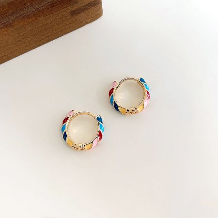 A pair of small gold huggie earrings featuring bright rainbow enamel colors.