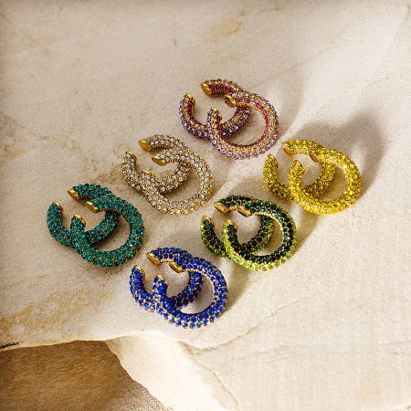 A collection of gold-colored ear cuff clip earrings featuring different colored rhinestones, including blue, green, and pink.