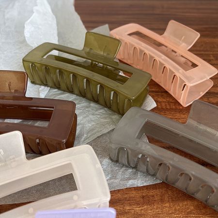 A display of large rectangle hair clips in various colors including pink, green, white, and grey.