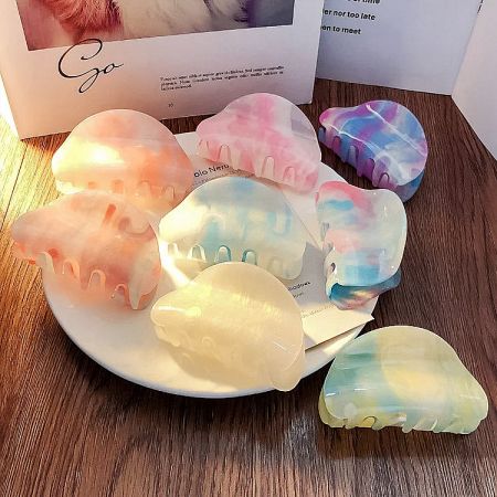 A display of colorful marbled acetate hair claws on a wooden surface.