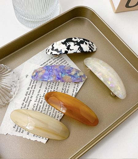 Assortment of colorful acetate hair clips displayed on a decorative gold tray.