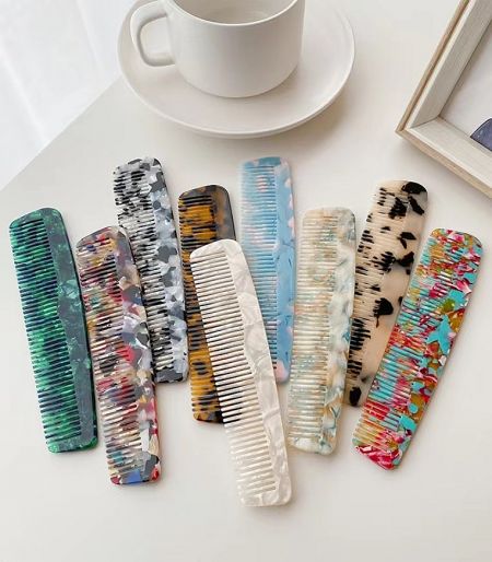 A vibrant assortment of stylish acetate hair combs in various colors.