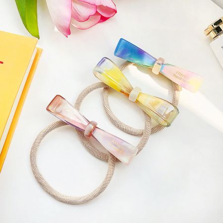 Close-up of several colorful bowknot hair ties showcasing the glossy acetate material.