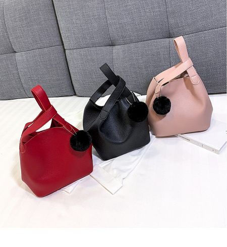 A collection of vibrant mini tote bags in different colors, each with a matching pom-pom charm.