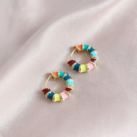 Detailed shot of the colorful hoop earrings, showcasing the gold base and intricate multi-color enamel details.