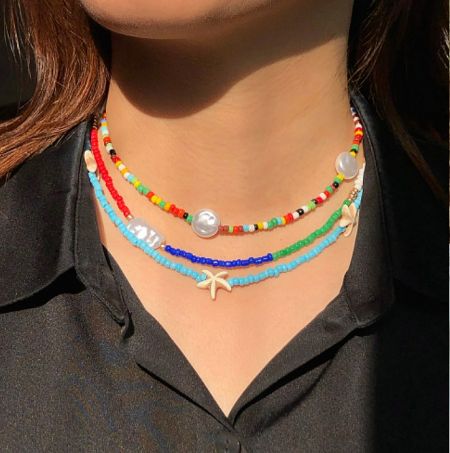 A model showcasing the stylish look of layered multi-color seed bead necklaces.