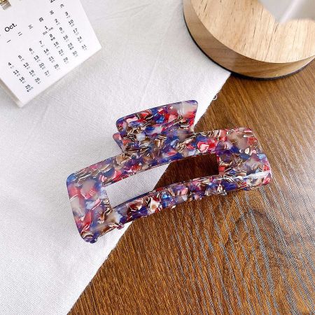 A pair of vibrant hair clips with a colorful red, blue, and gold marble design.