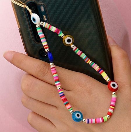 Close-up of a colorful phone charm with eye-shaped beads attached to a smartphone case.