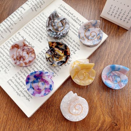 Small Conch Shell Shape Acetate Hair Claw Clips (Set of 5) - A vibrant collection of small conch shell-shaped acetate hair claw clips in various marbled colors, displayed on a wooden surface.