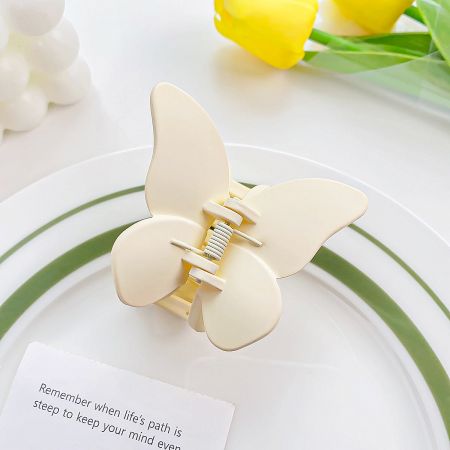 Elegant cream-colored butterfly hair claw on a decorative plate.