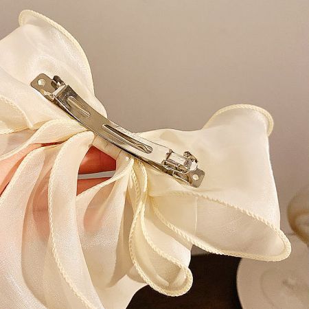Close-up view of the cream-colored bow's back, showing the durable silver French clip.