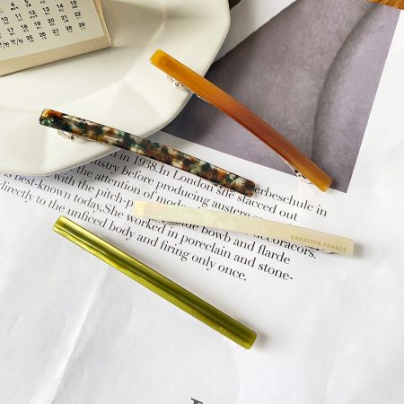 Three acetate hair clips in different colors and patterns, showcasing the product variety.