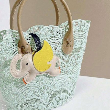 The whimsical white elephant leather charm adding a playful touch to a beige crochet tote bag.