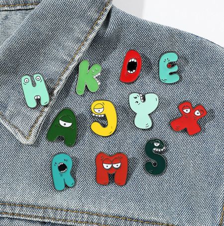 Custom enamel letter pins displayed on a denim jacket, demonstrating a popular use case.