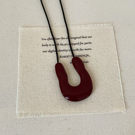 The striking dark red U-shaped pendant necklace, a bold statement piece.