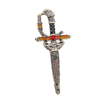 Close-up of a decorative sword brooch featuring a snake-shaped hilt with orange and red gemstones.