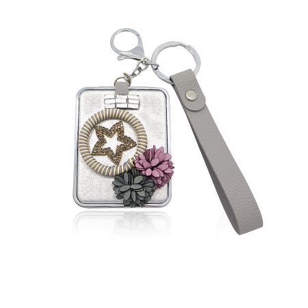 Wrist Strap Decorated Compact Mirror At Wholesale - A stylish wrist strap decorated compact mirror, featuring an elegant rectangular case with a star and floral design.
