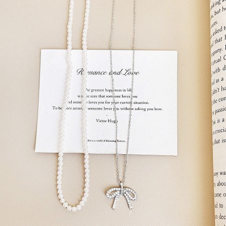 The sterling silver bow-knot zircon necklace displayed elegantly on a romantic quote background.