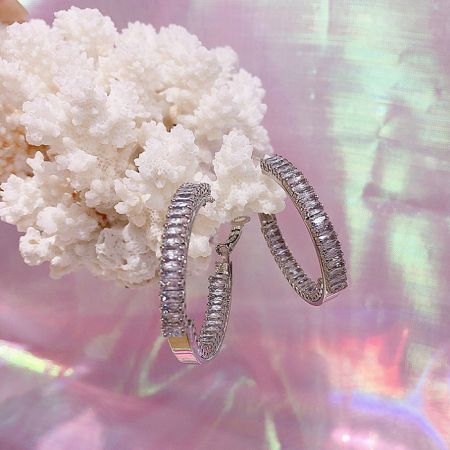 The 40mm CZ hoop earrings displayed against a vibrant coral background to emphasize their sparkle.