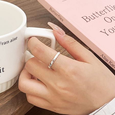 A sterling silver open ring from the set of 5 displayed elegantly on a book.