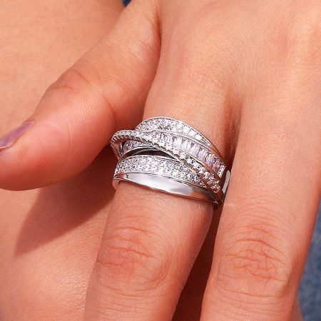 Detailed product shot of the multi-layered cubic zirconia brass ring set on a soft pink background.
