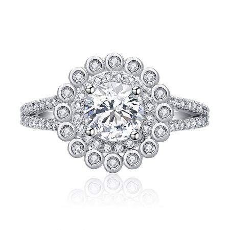 Round Cut Split Shank Engagement Ring - A close-up view of the Round Cut Split Shank Engagement Ring, featuring a brilliant cubic zirconia center stone in a halo setting on a rhodium-plated band.