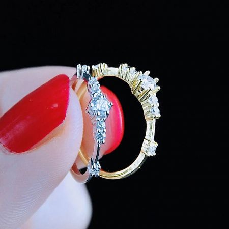 A hand holding both the silver and gold versions of the 925 sterling silver zircon rings, showcasing the available finishes.