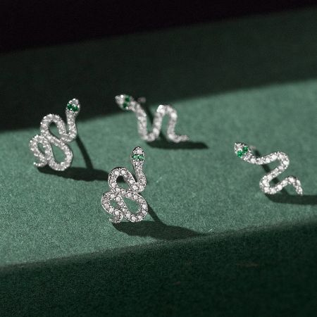 Detailed view of the diamond-encrusted snake earrings highlighting the green gemstone eyes.